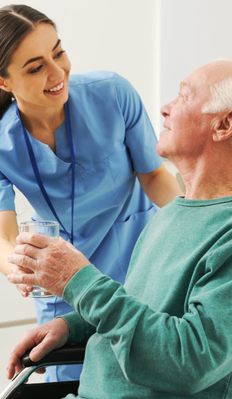 a female caregiver serving a glass of water to an elderly man